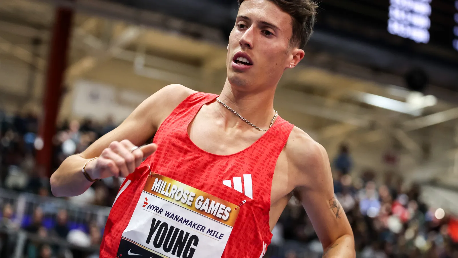 Male runner in red Adidas singlet competes in the Millrose Games Wanamaker Mile indoor track race
