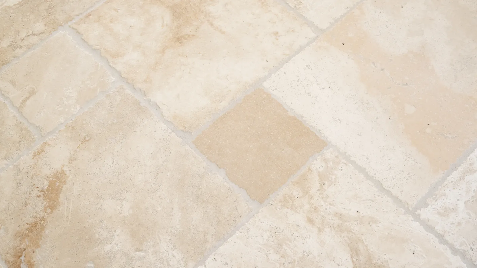 Close-up of textured beige stone tiles with varied patterns and shades.