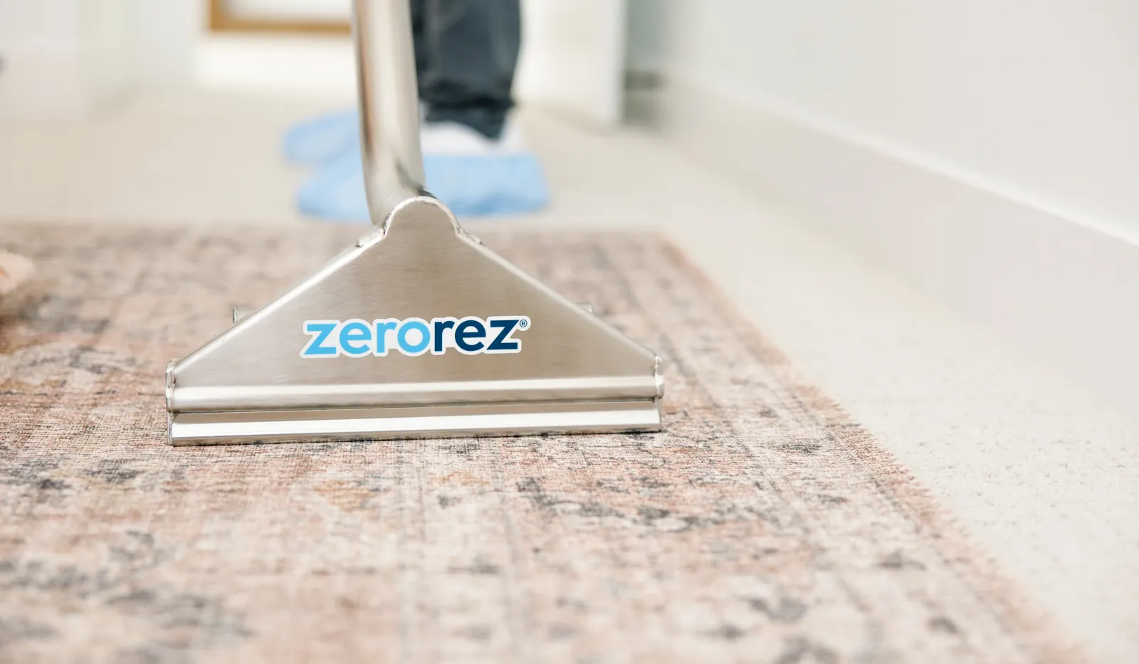 Professional carpet cleaning machine with Zerorez logo cleans a patterned rug on a light floor indoors.