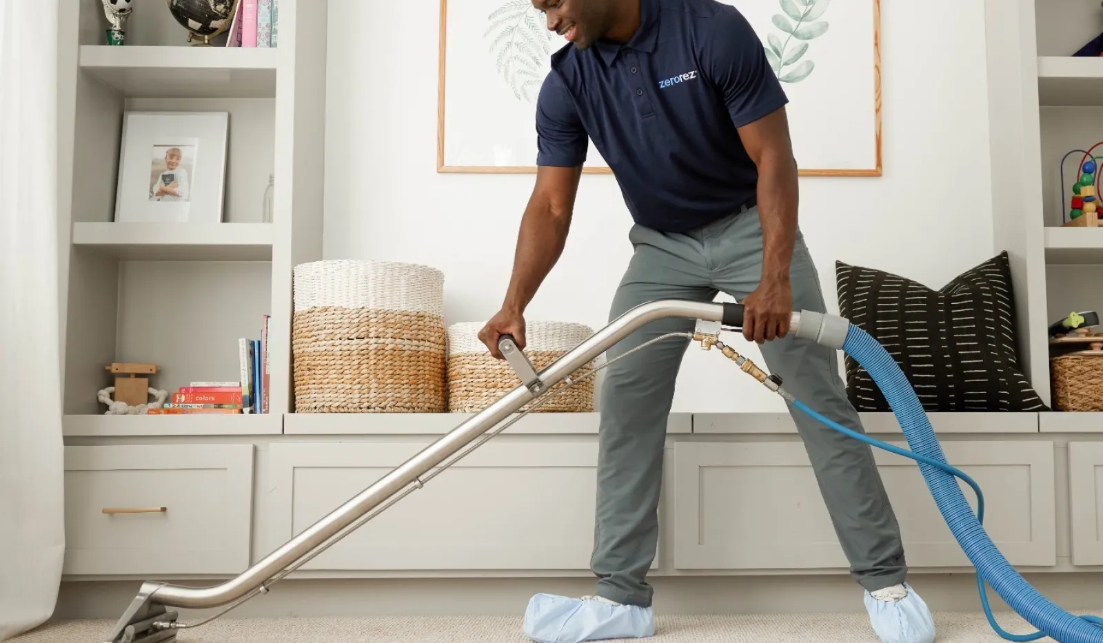 A professional cleaner using a carpet shampooer on beige carpet in a cozy living room.