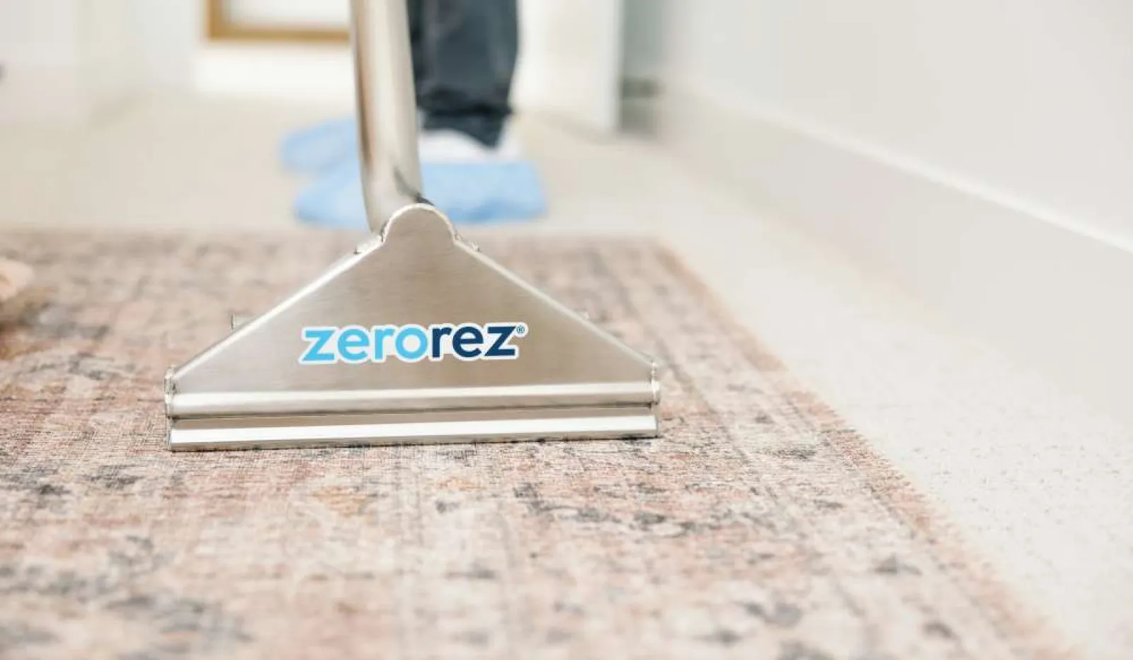 Professional carpet cleaning machine with Zerorez logo cleaning a patterned rug in a bright room.