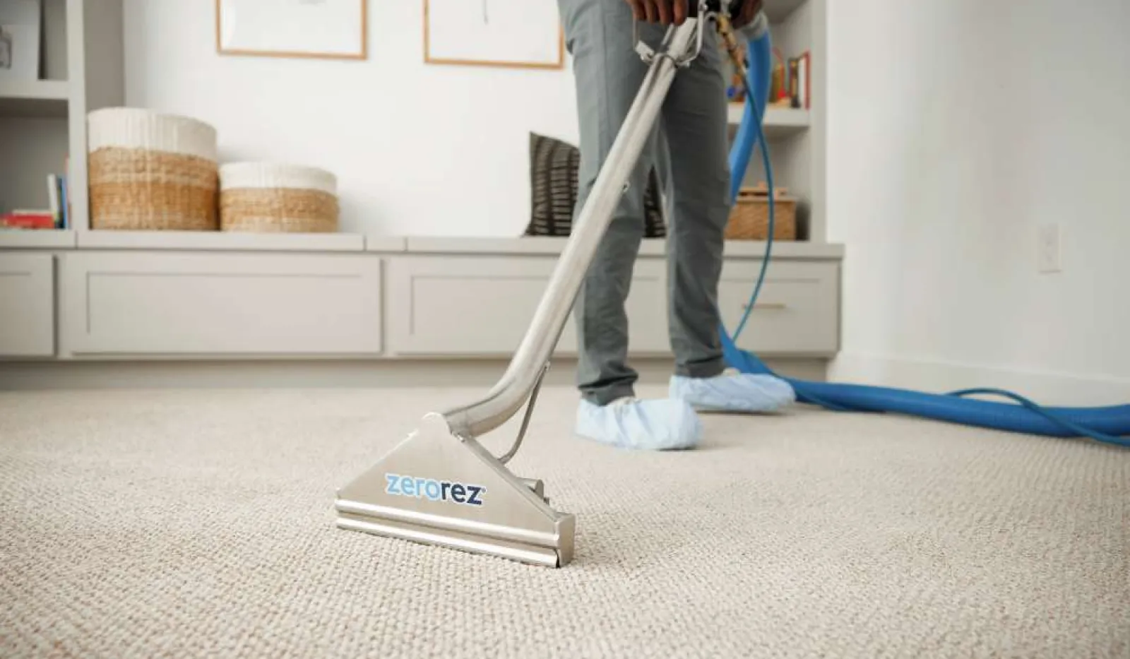 Professional technician cleaning beige carpet with Zerorez cleaning tool in modern living room setting.