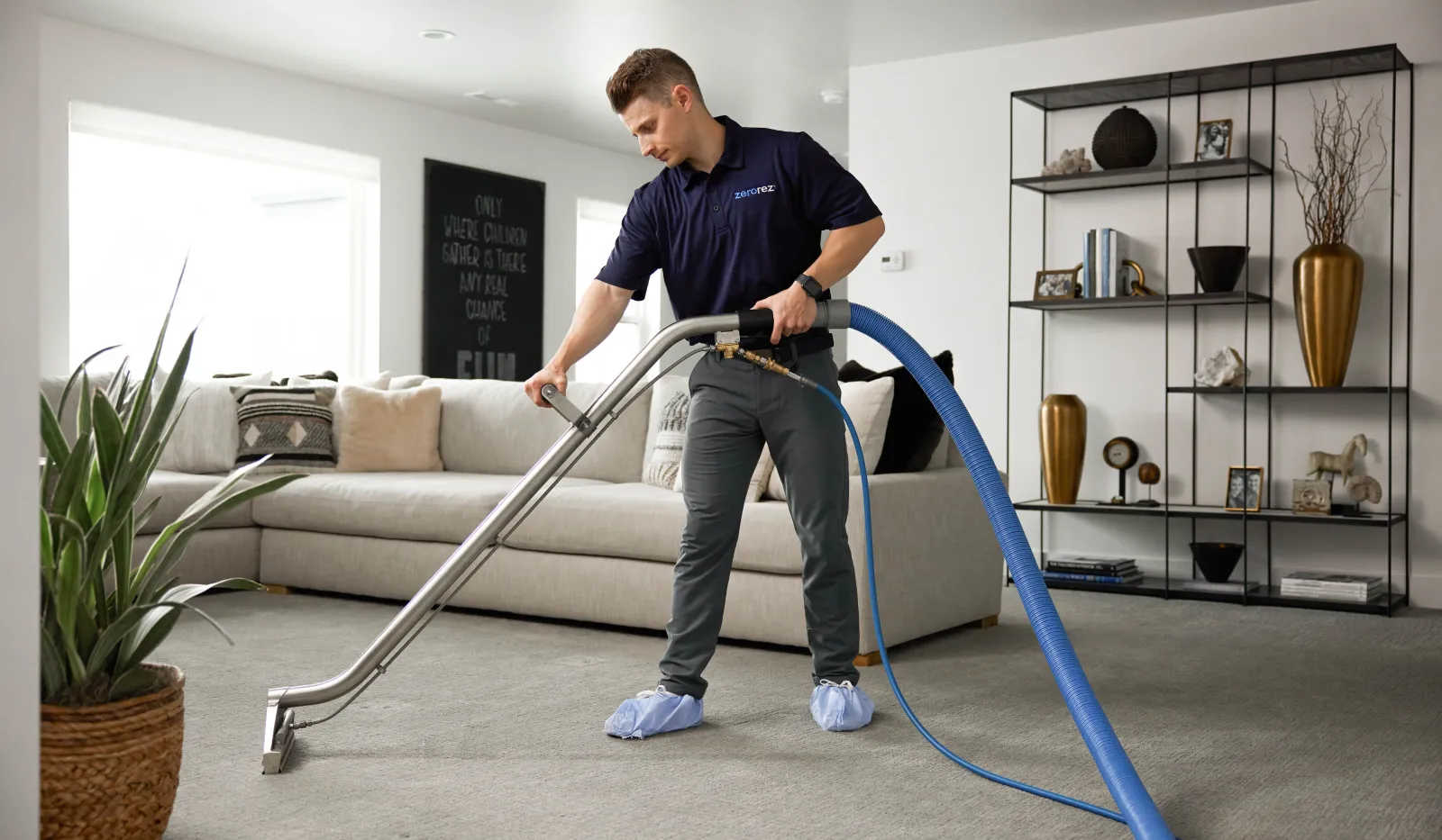 Professional cleaner using industrial vacuum to deep clean carpet in modern living room with sofa and decor.