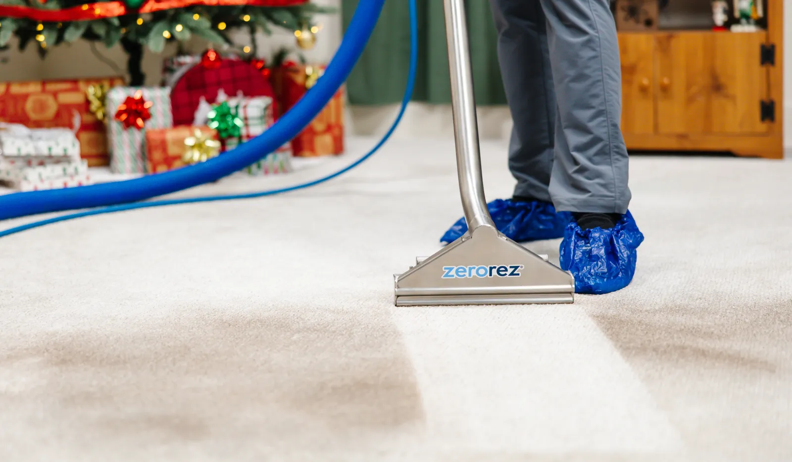 Professional carpet cleaning in a decorated living room with Christmas tree and wrapped gifts.