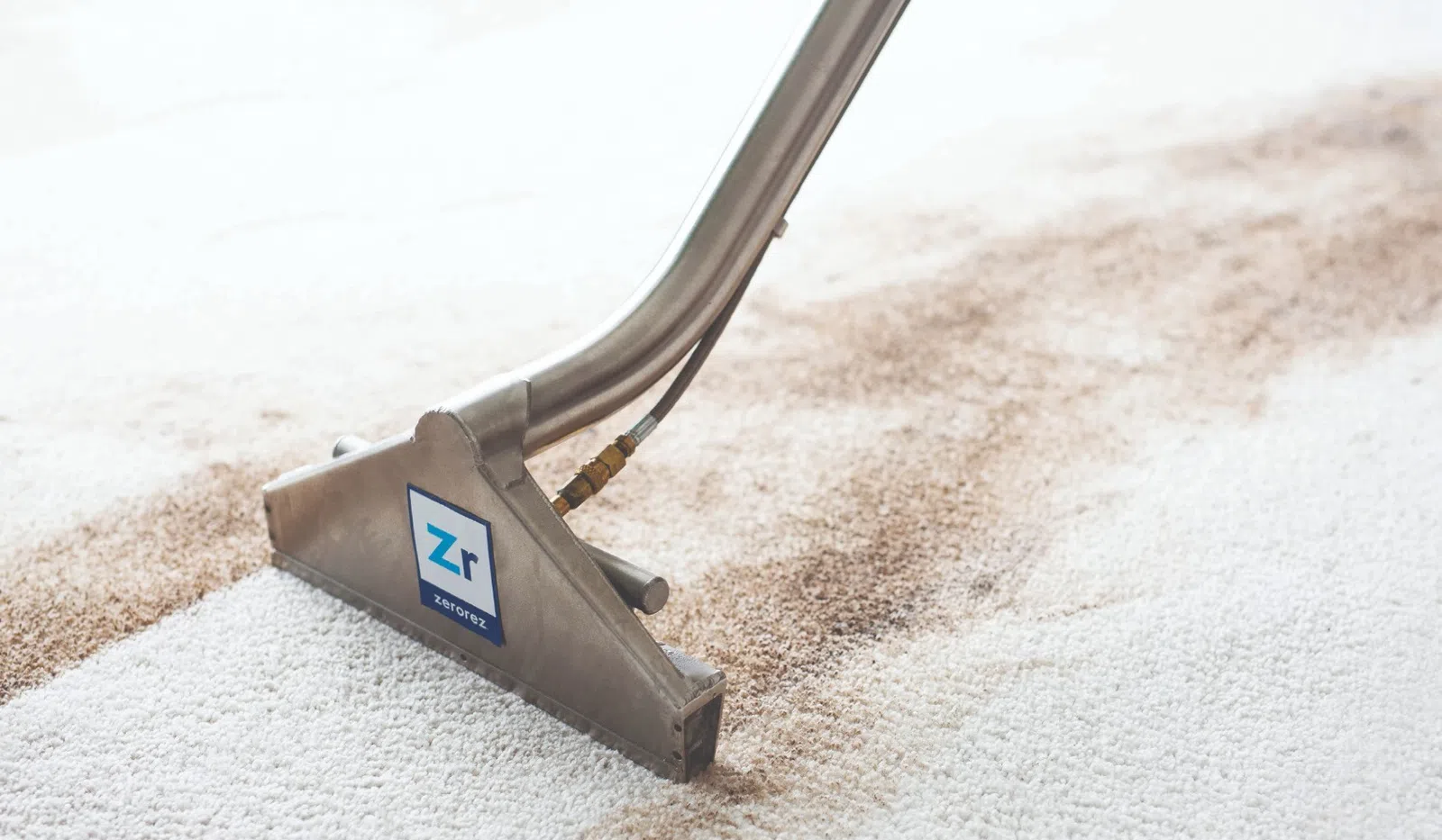 Carpet cleaning tool removing dirt and stains from white carpet with visible clean and dirty areas