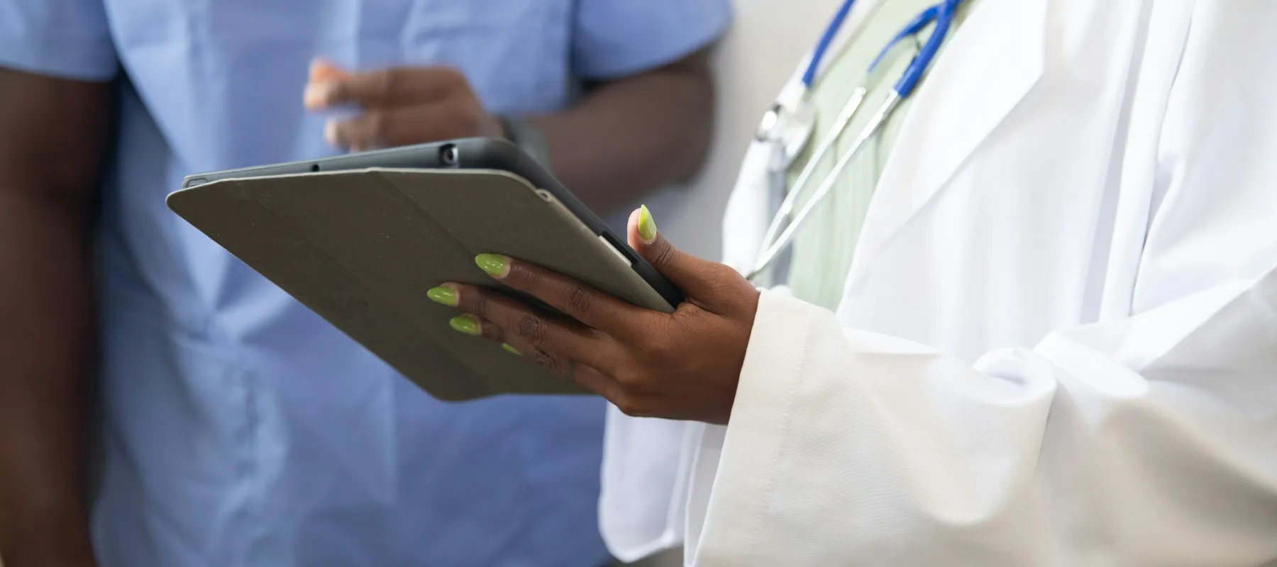 Close-up of healthcare professionals reviewing information on a tablet during medical consultation.