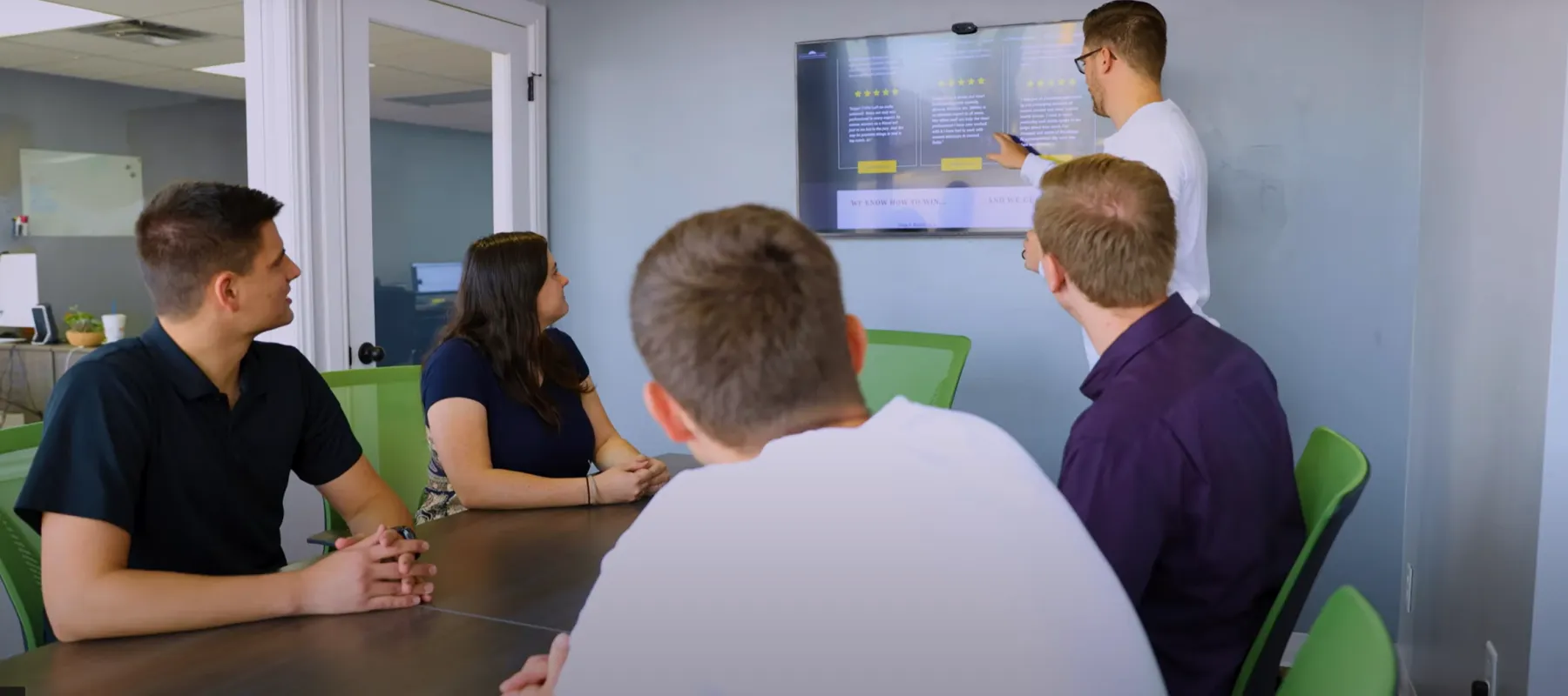 a group of people sitting at a table looking at a screen