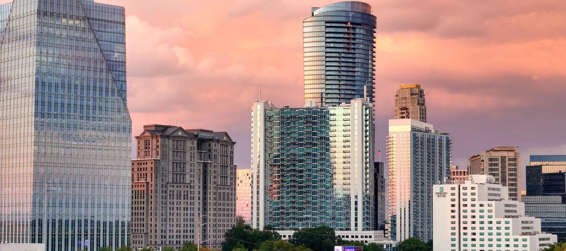 Buckhead city skyline with high-rise buildings under a vibrant pink and orange sunset sky.