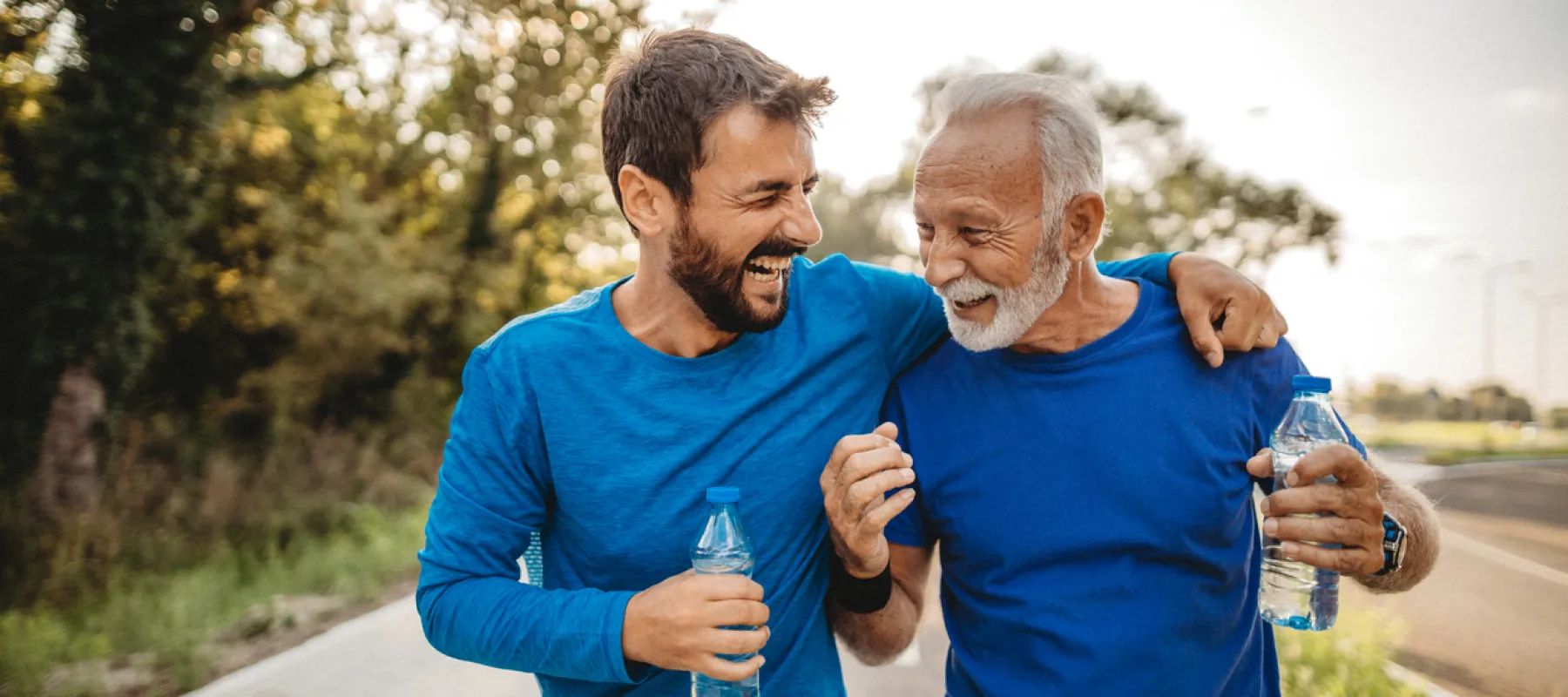 two men embracing while holding water bottles