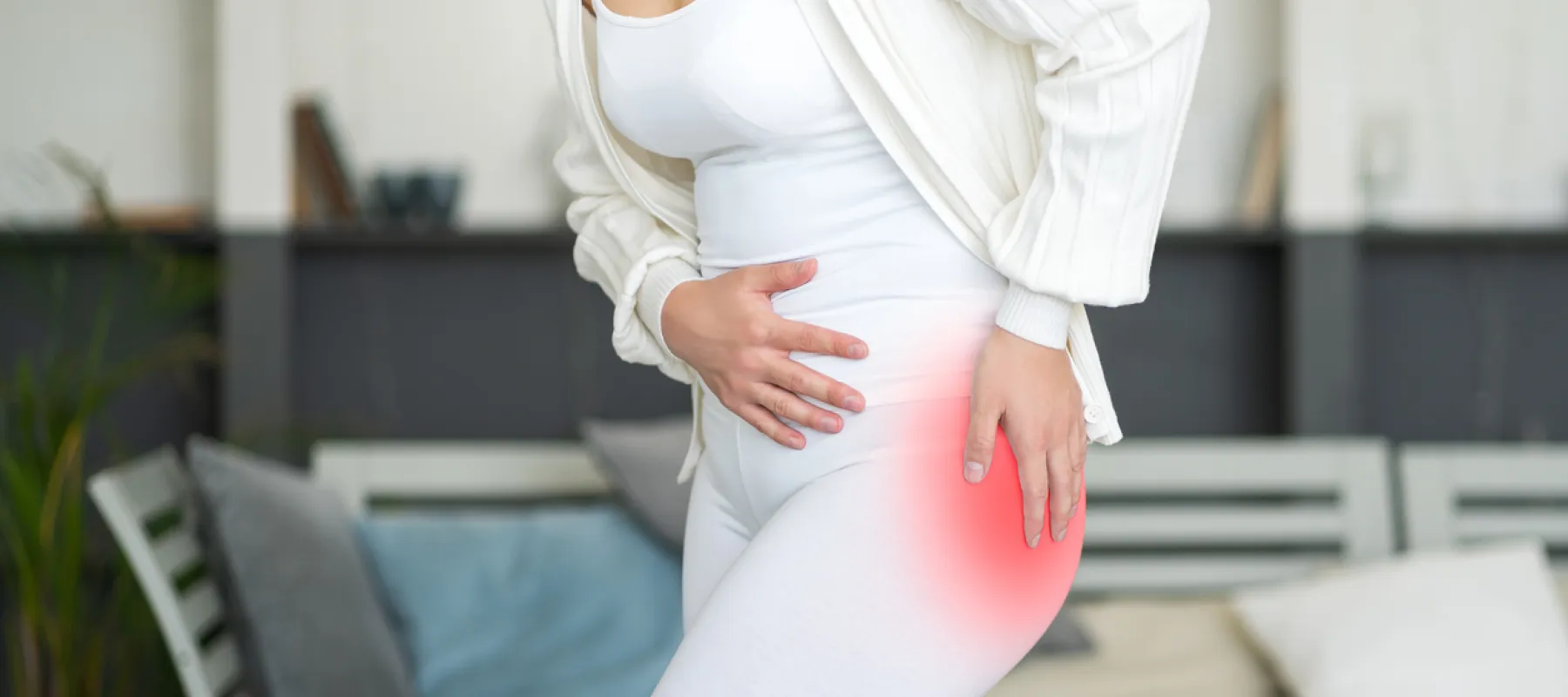 Woman in white outfit holding her hip with red highlight indicating pain or discomfort in hip area.