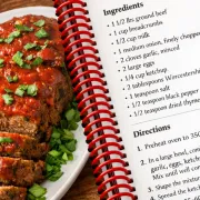Open spiral-bound cookbook displaying a colorful recipe photo, a list of ingredients, and directions.