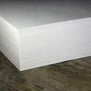 A stack of white paper lying on a wooden surface