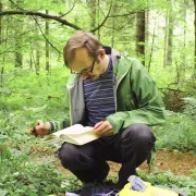 A man reading a field guide in the woods