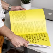 A person reading through a large book with yellow pages
