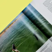 An open magazine with a Crossover Image of a fisherman spanning both pages