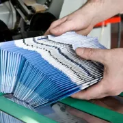 A stack of printed brochures exiting the folding machine
