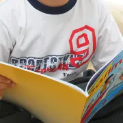 A boy holding open a softcover story book