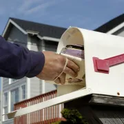 A mail carrier placing mail into a mailbox