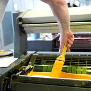 Man adding yellow ink to an offset printing press