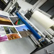 A commercial laminator applying plastic film over full color print project