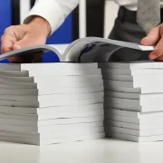 A man holding an open book over two stacks of books