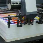 Commercial printing press producing colorful printed sheets.