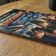 Thick comic book named Operation Shockwave The Dead Zone with explosions and city destruction on cover lying on a wooden table.