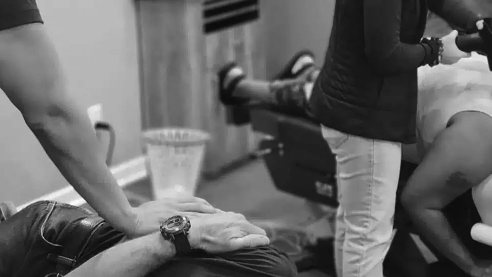 Two therapists performing manual and percussion massage on clients lying on therapy tables in a clinic.