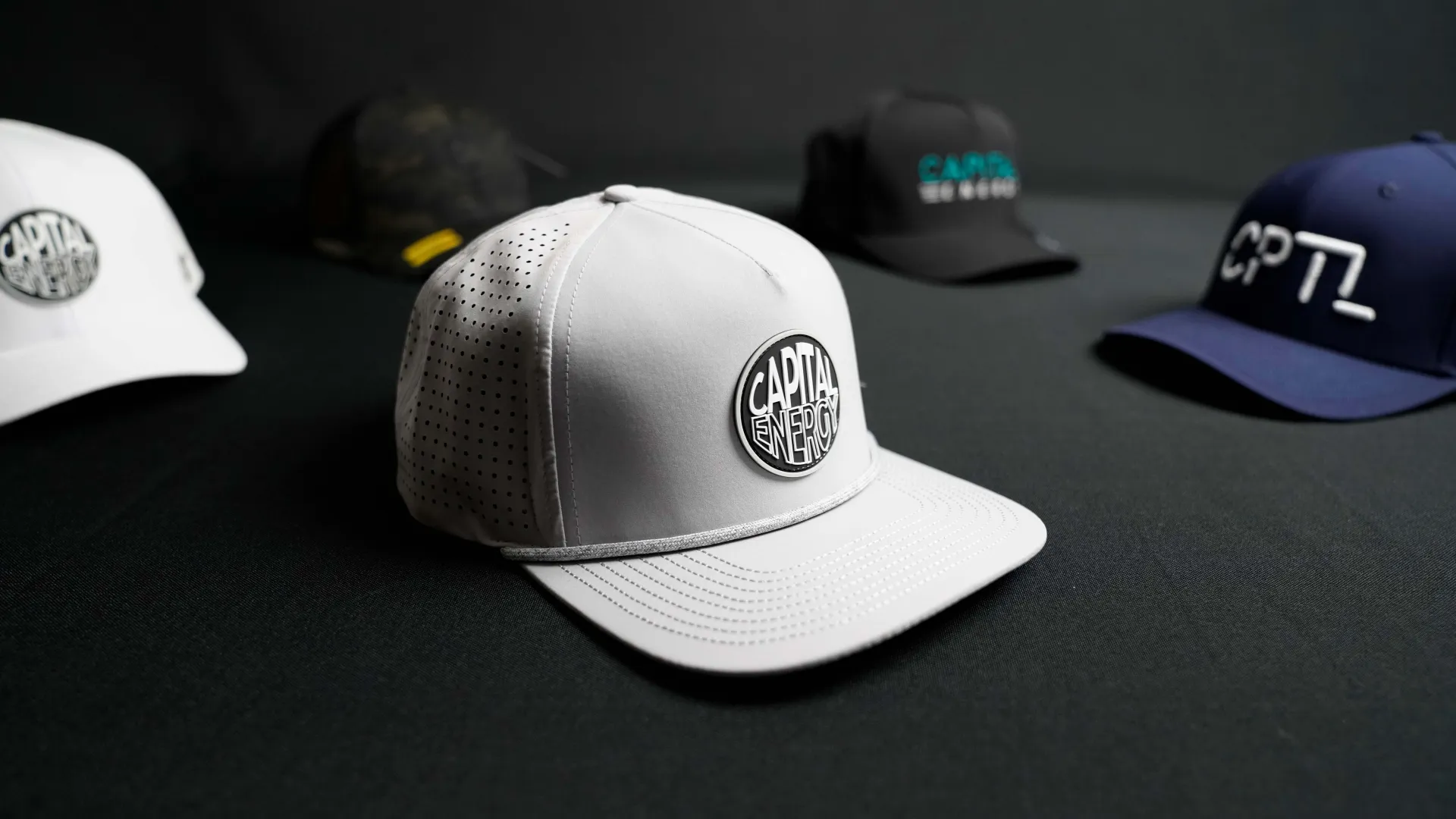 Stylish caps on display, prominently featuring a grey cap with 'Capital' logo at the forefront.