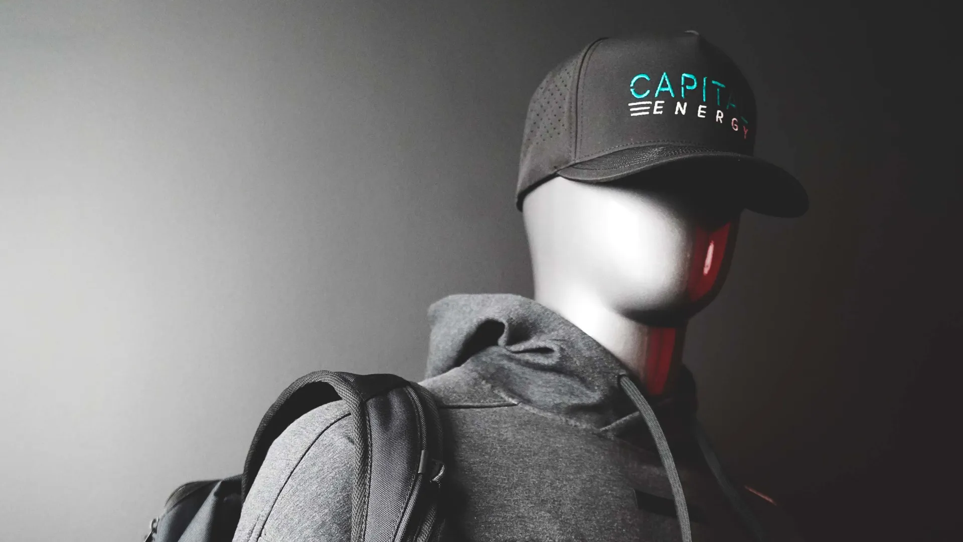 Model wearing Capital Energy cap and hoodie with a dark background.
