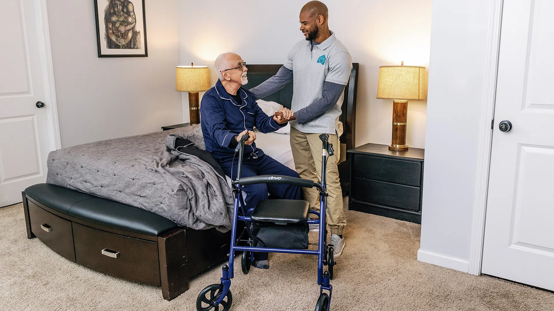 Caregiver assisting an elderly man with a walker in a comfortable bedroom setting.