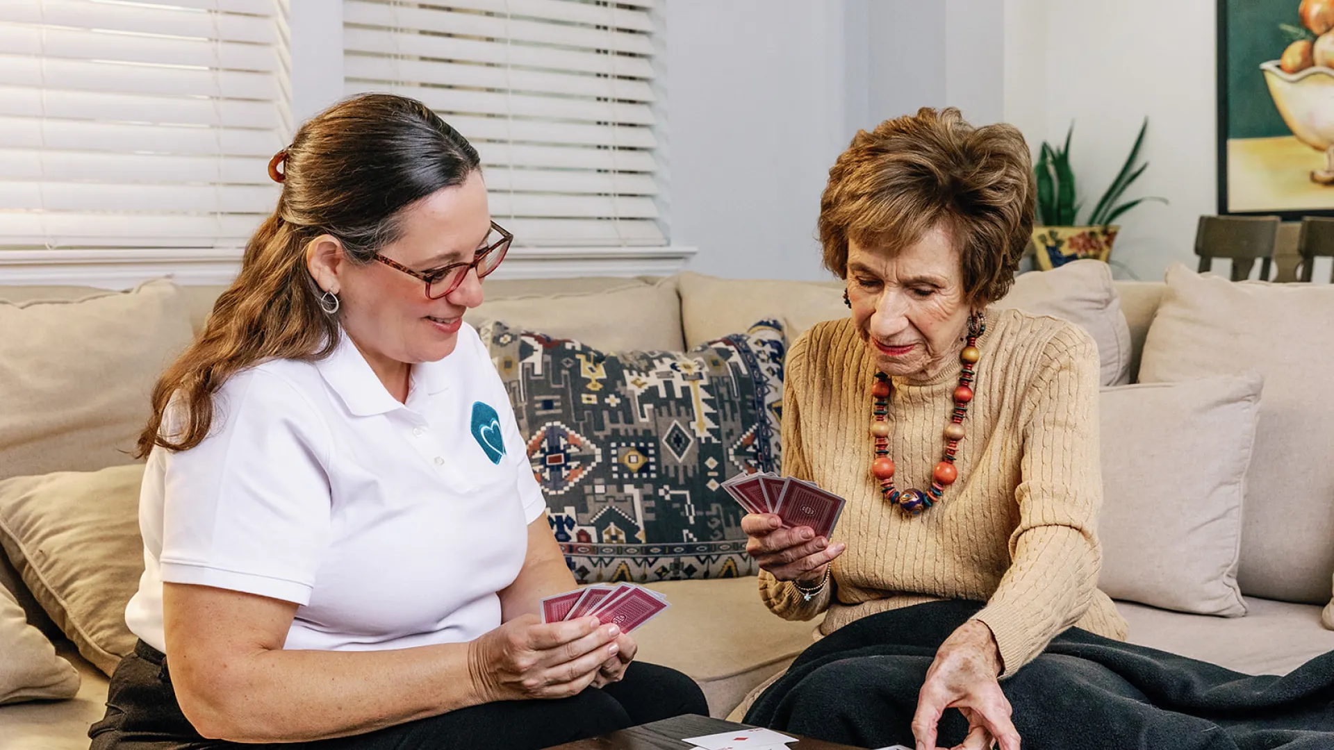 a couple of women playing cards on a couch