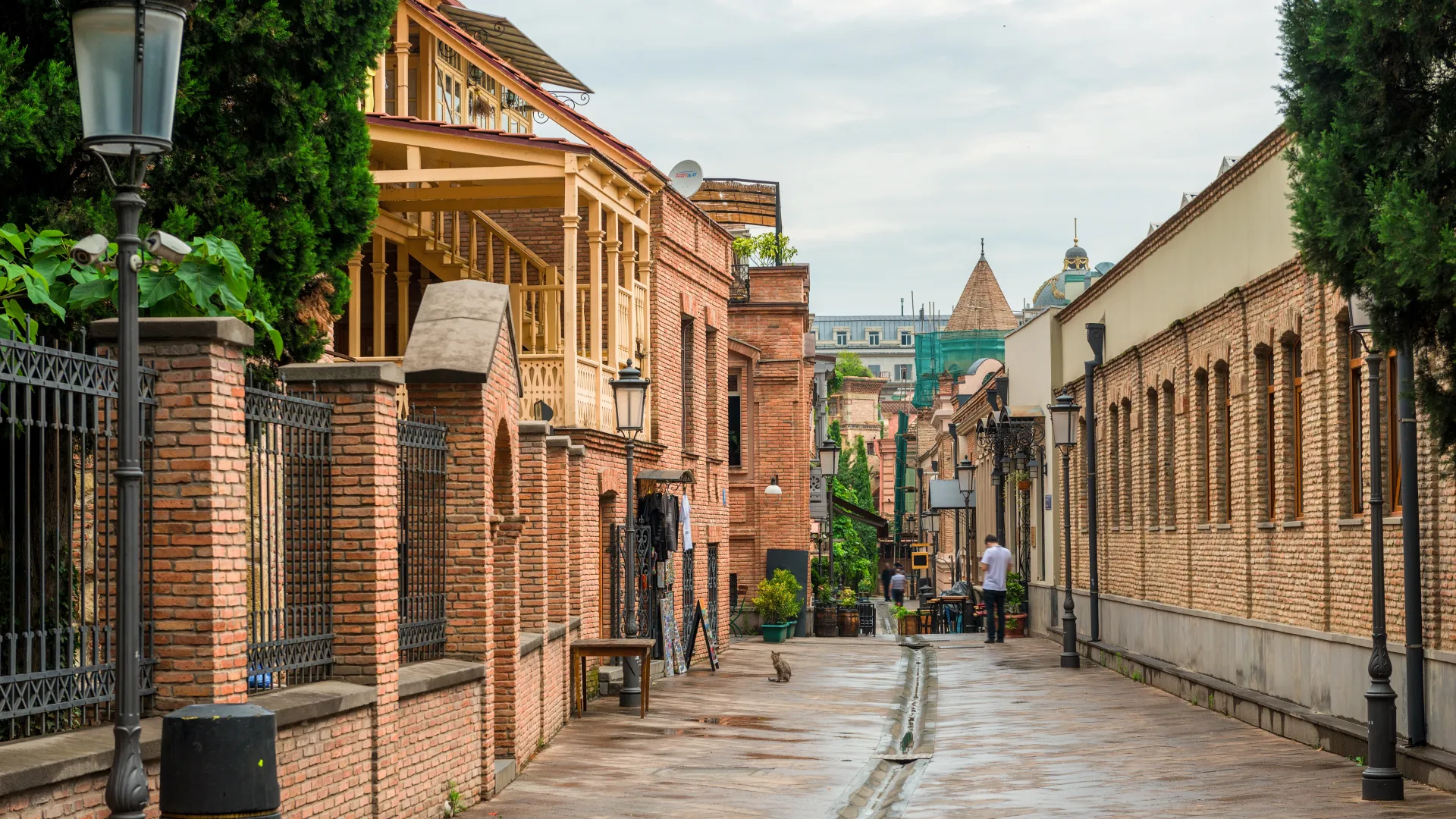 Narrow street with red brick buildings and vintage lamps in a quiet urban neighborhood on a cloudy day