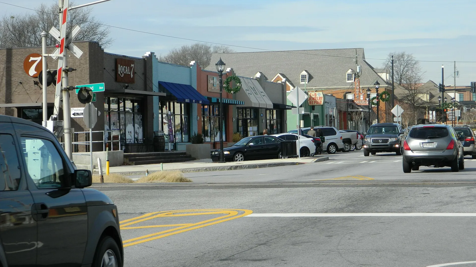 main street in tucker ga with shops, parked cars, Christmas wreath decorations, and a railroad crossing signal on a clear day
