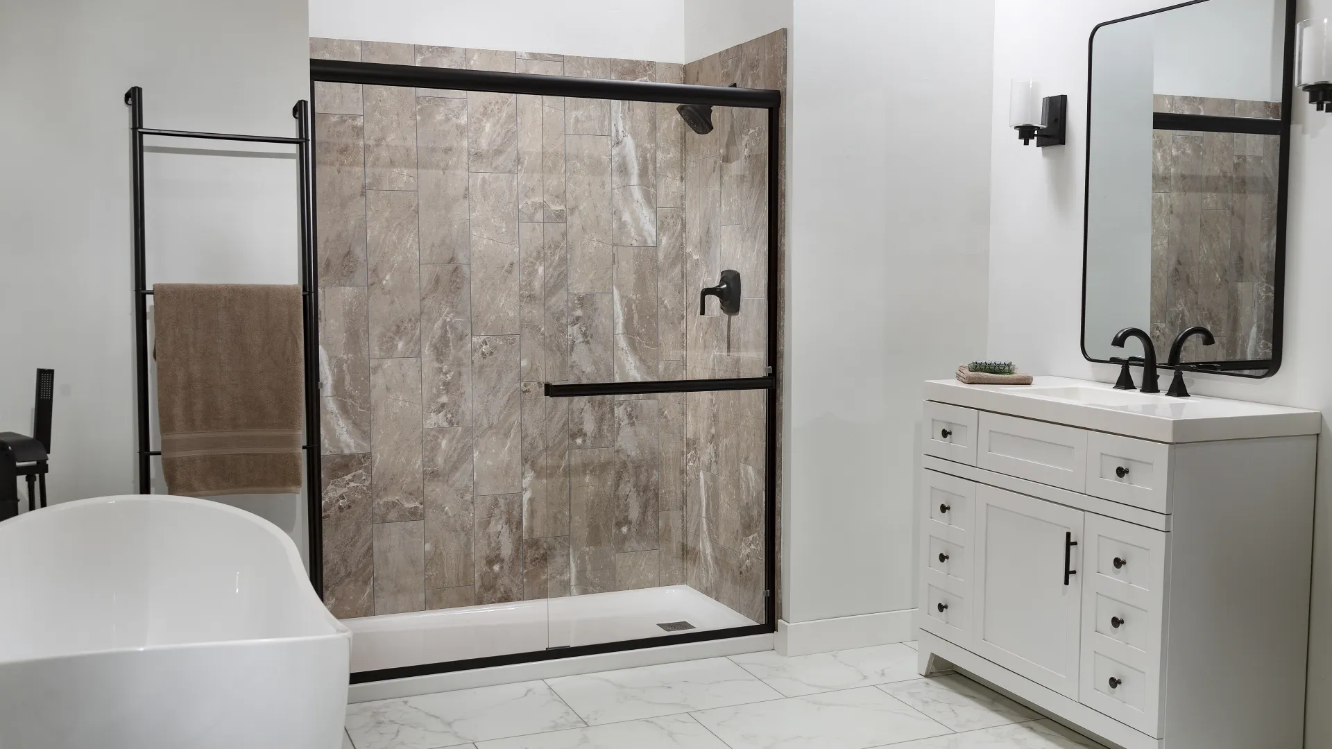 Modern bathroom with white freestanding tub, glass shower with brown tile, white vanity, and large mirror.