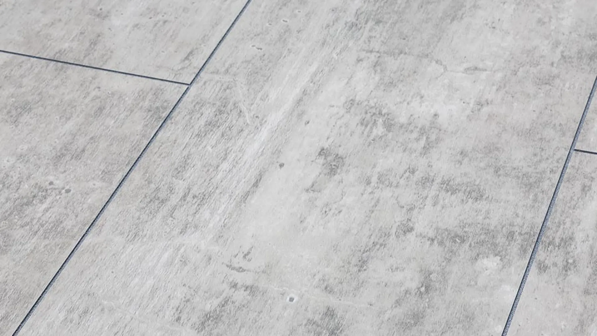 Close-up of light gray textured ceramic floor tiles with subtle veining and grout lines.