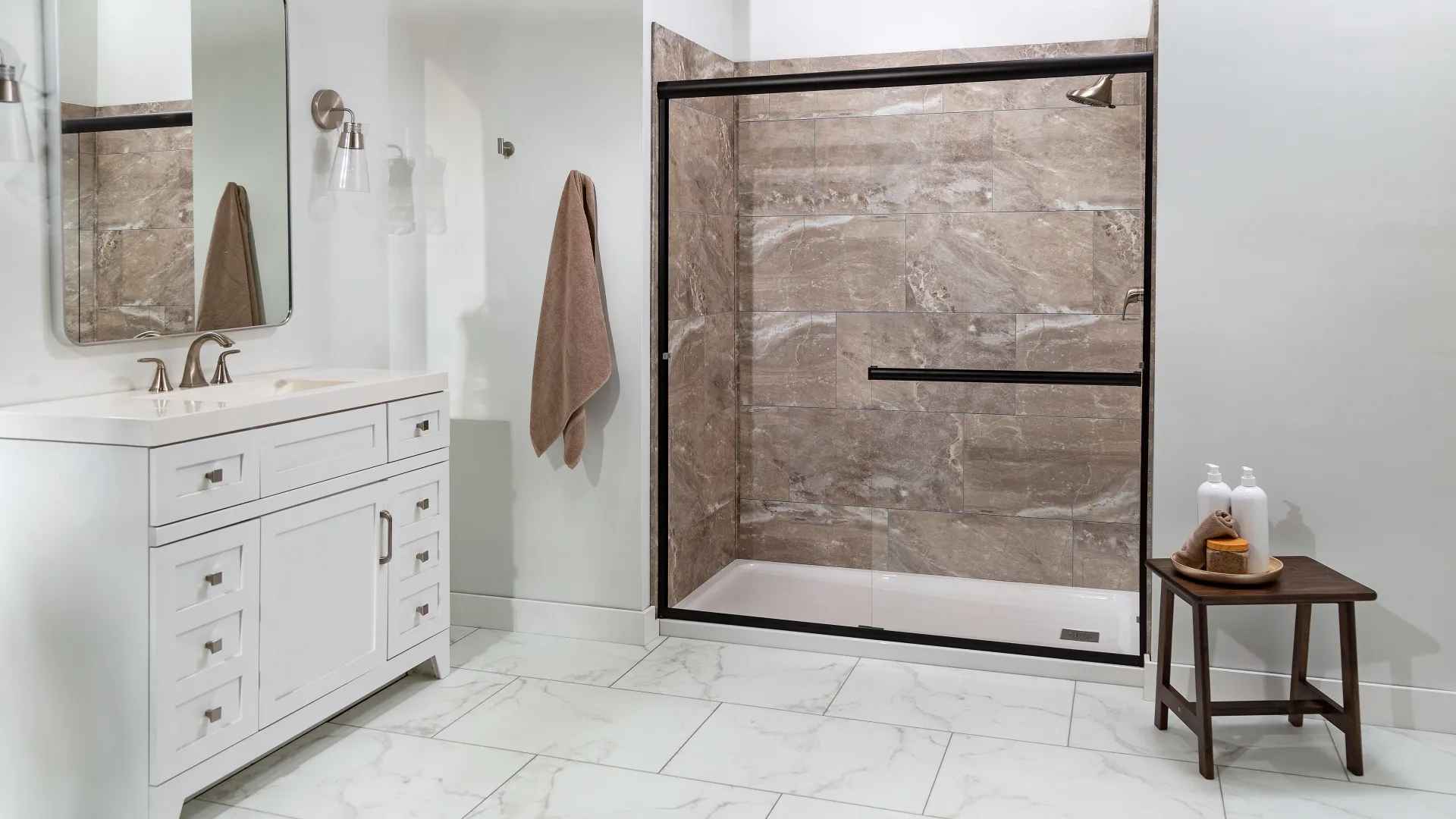 Modern bathroom with white vanity, beige tiled walk-in shower, and marble-look floor tiles