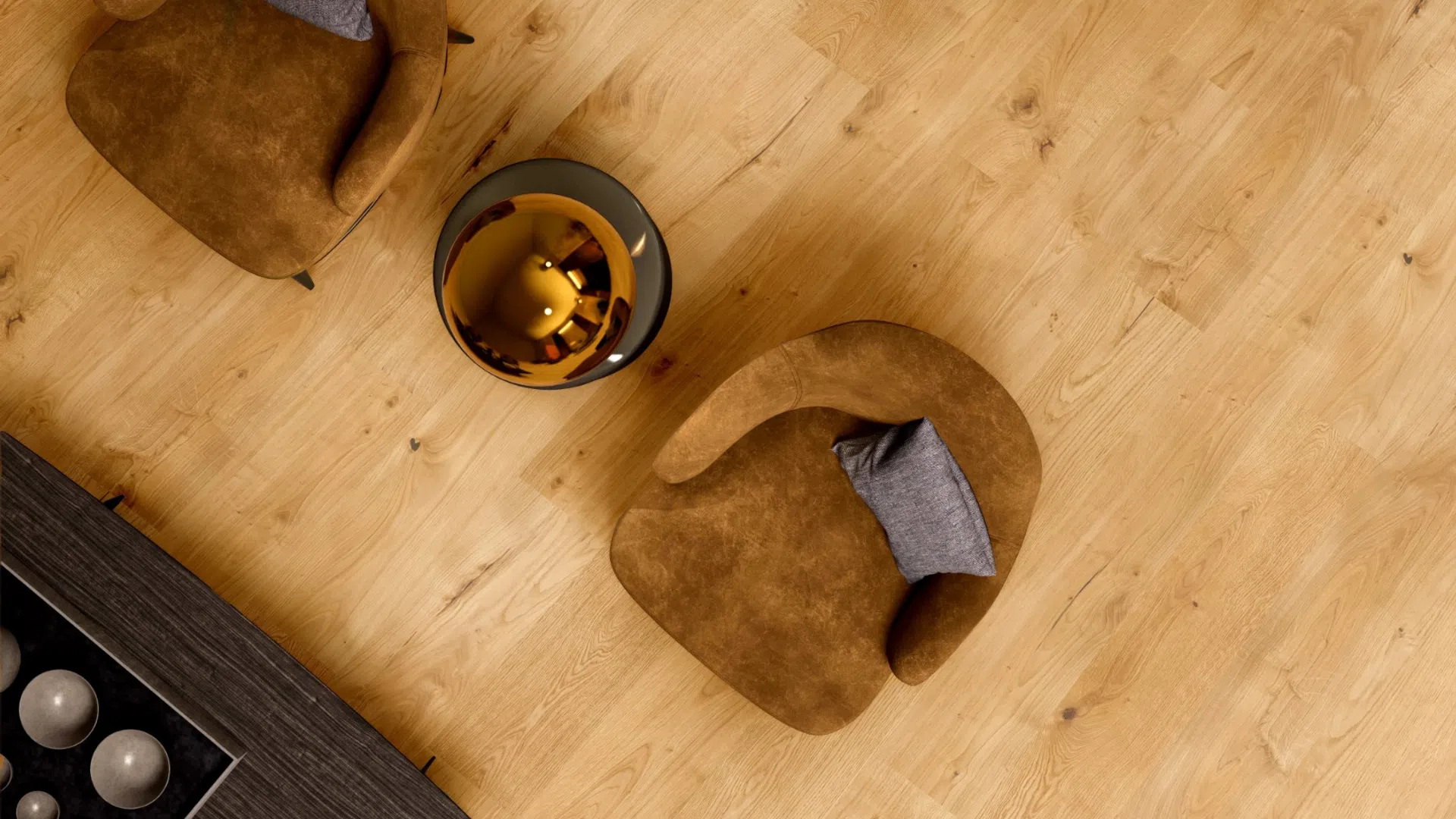 Top-down view of two brown armchairs with gray pillows and a round shiny coffee table on wooden floor.