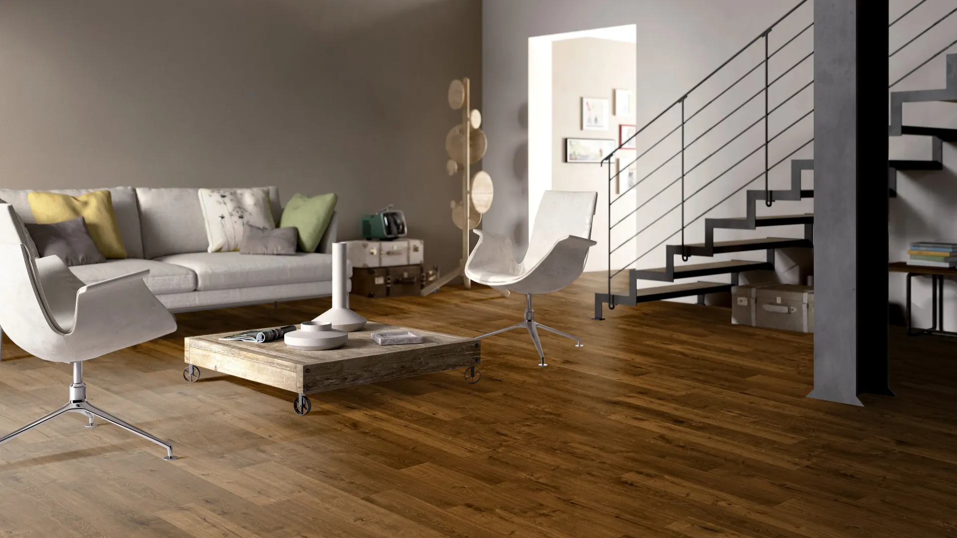 Modern living room with wooden floors, gray sofa, white chairs, coffee table, and metal staircase with loft bookshelves.