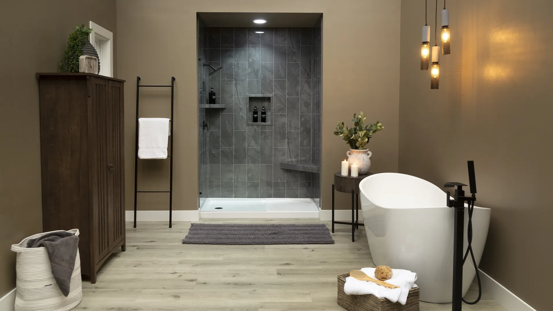 Modern bathroom with freestanding tub, walk-in gray tiled shower, wooden cabinet, and cozy decor.