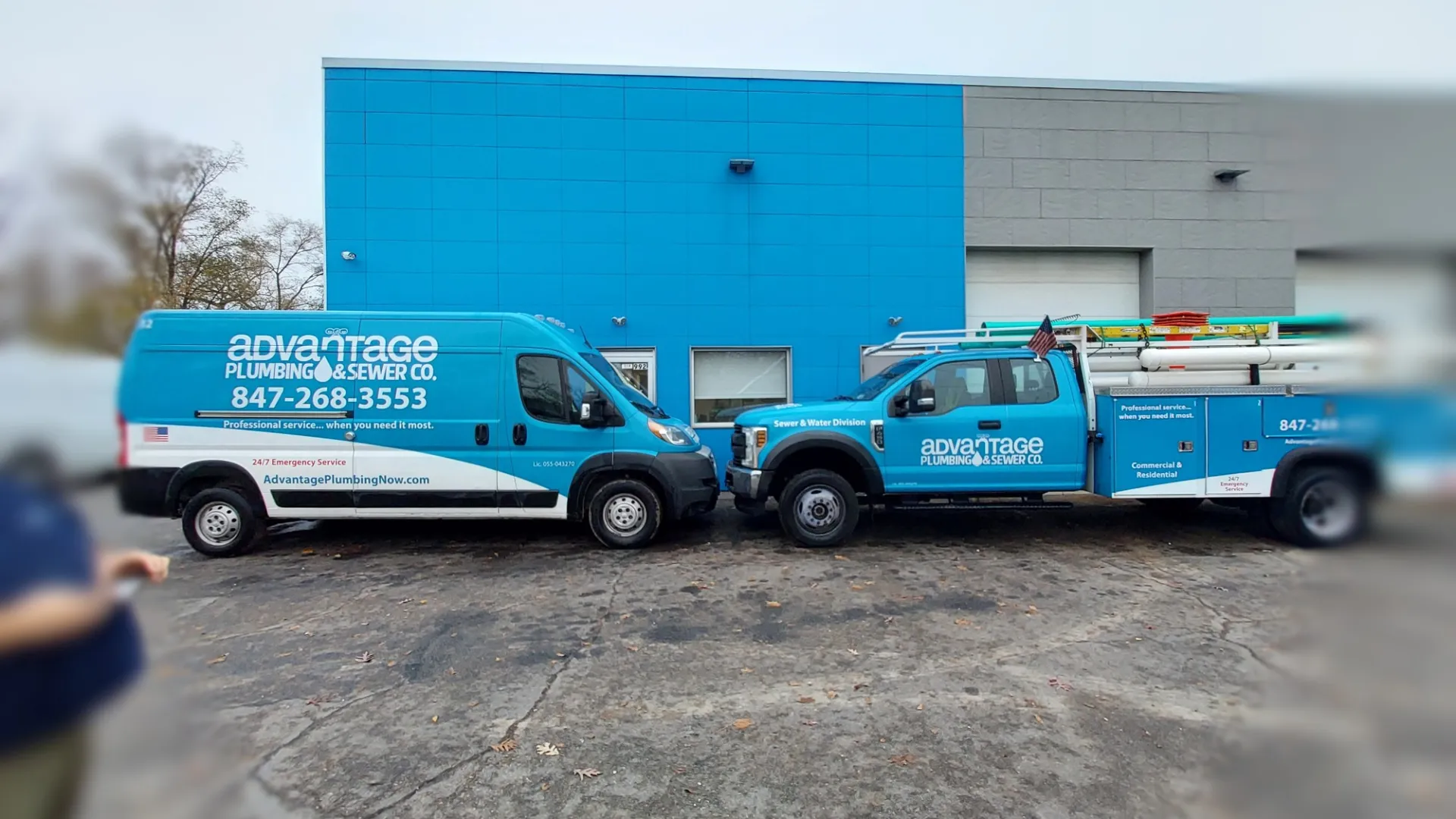 Blue Advantage Plumbing & Sewer Co. service van and truck parked outside a building with ladders and contact information visible.