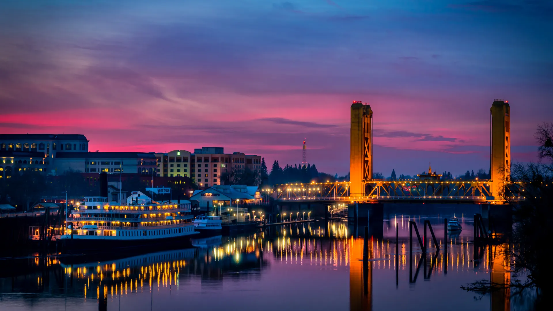 a city with a bridge and a river at sunset