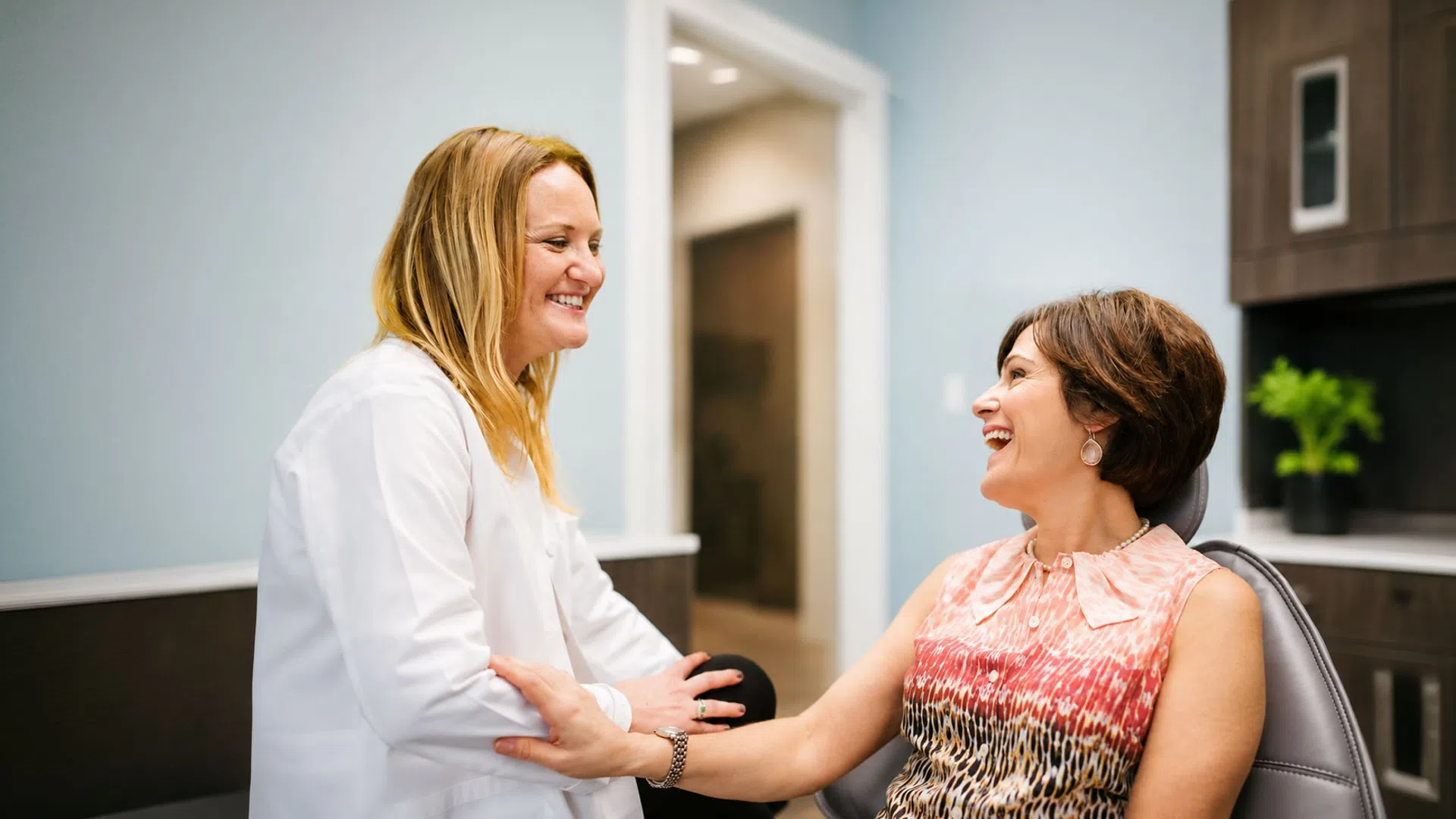 Smiling doctor and patient sharing a joyful moment in a modern medical office setting.