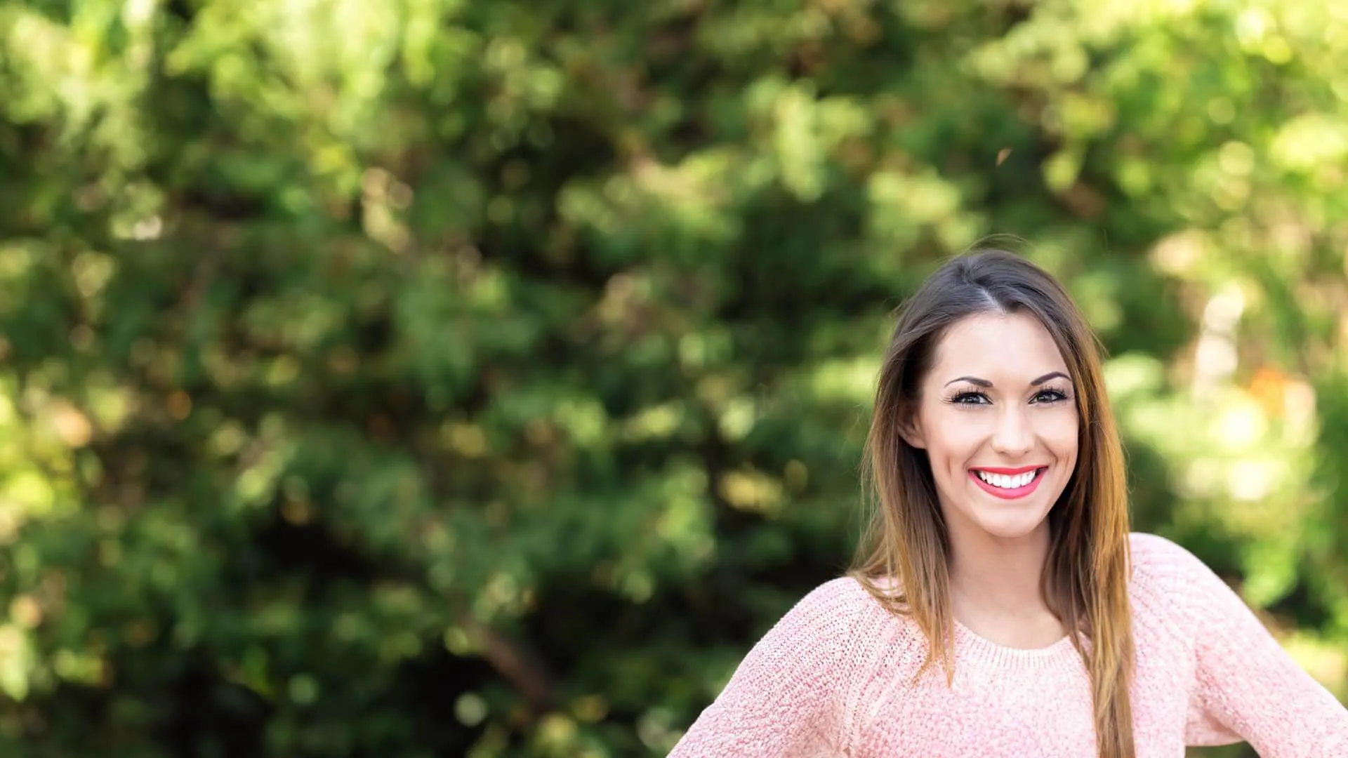 a woman smiling in front of a bush