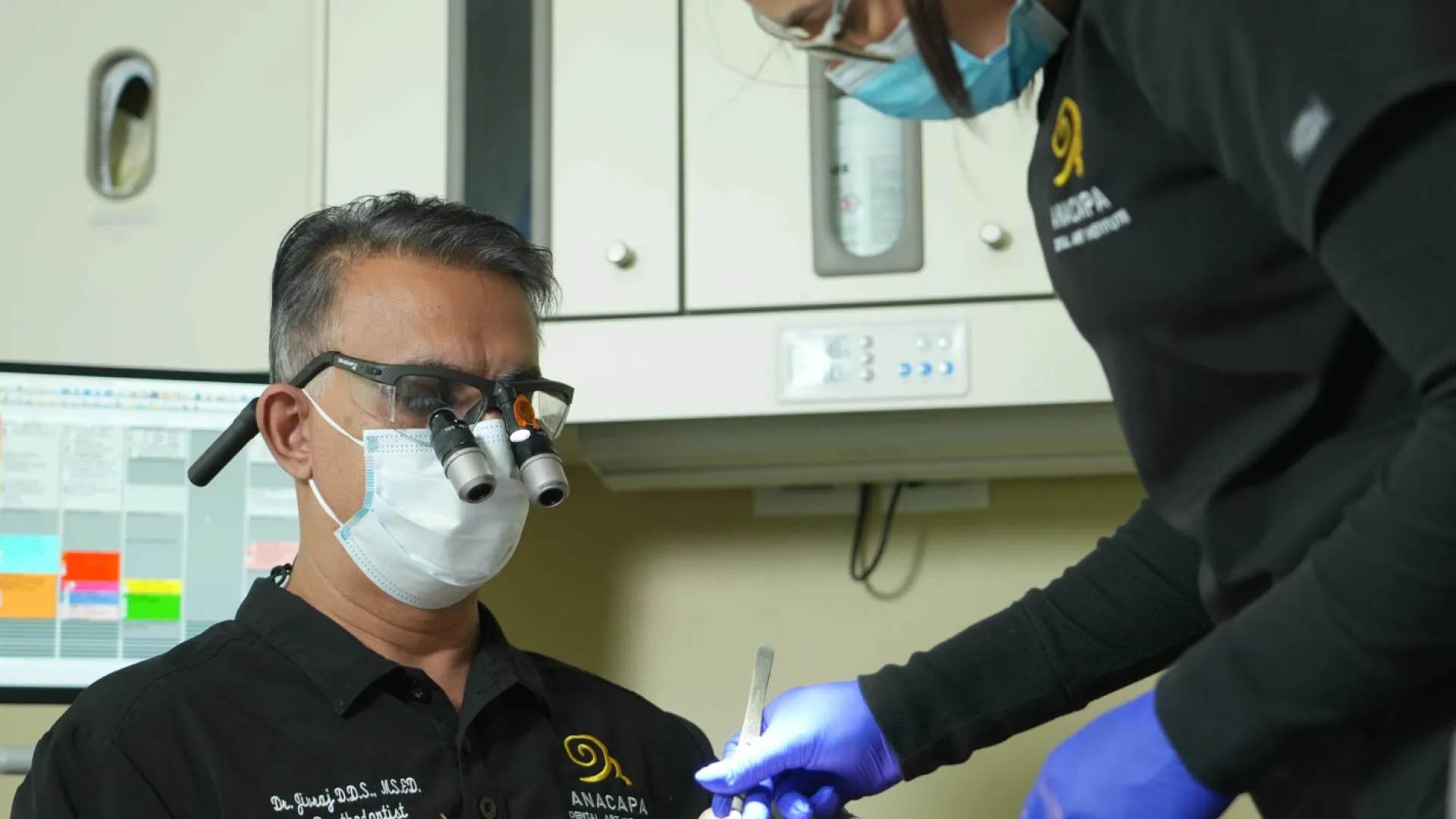 A dentist performs a procedure on a patient using specialized equipment and safety gear.