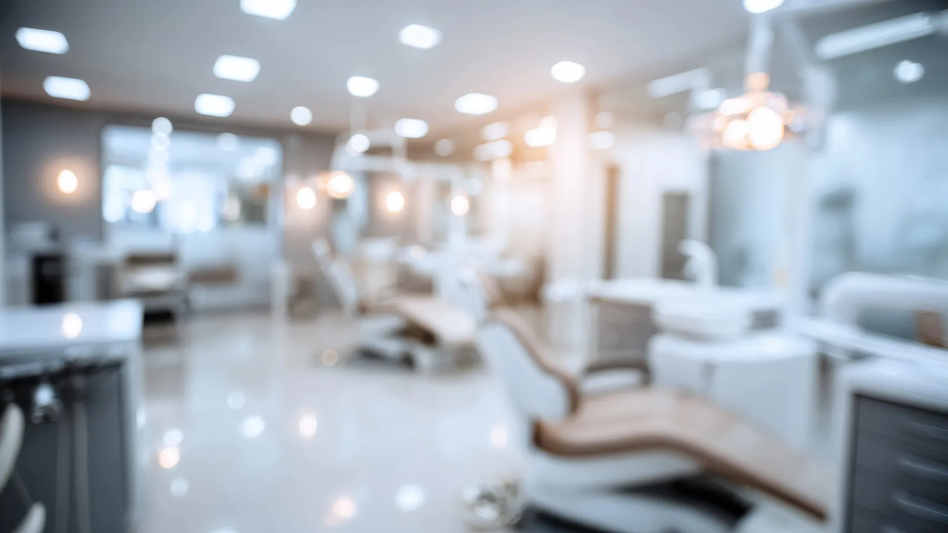 Blurred view of a modern dental office with dental chairs and bright lighting