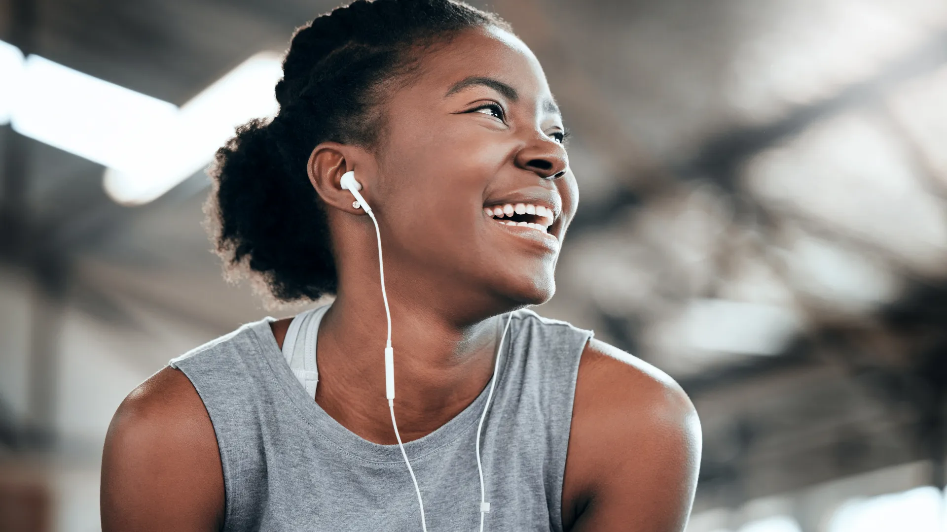 Smiling young woman wearing sportswear and earphones during a workout in a bright gym environment