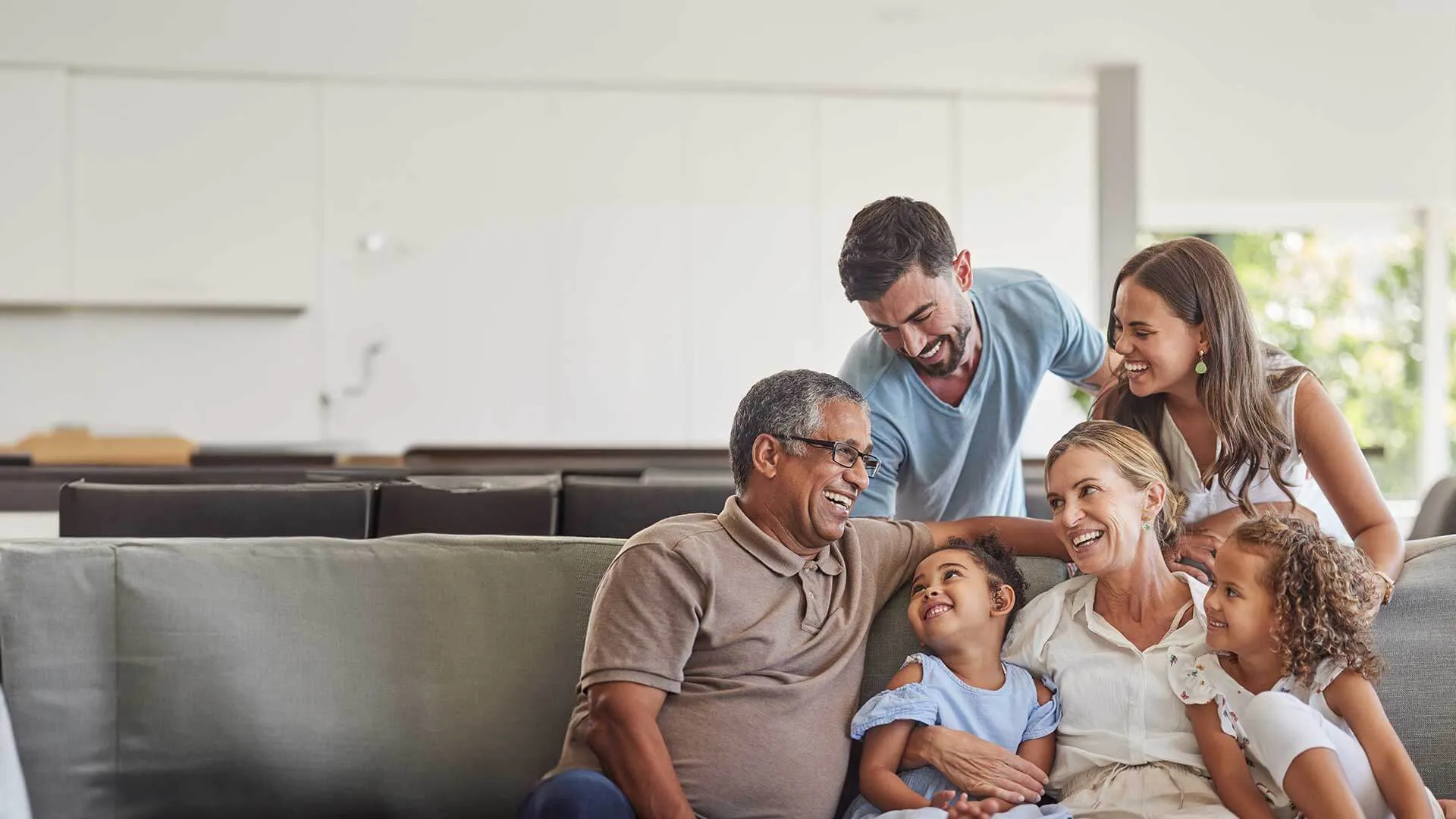 Happy multi-generation family smiling and spending quality time together on a couch in a bright living room