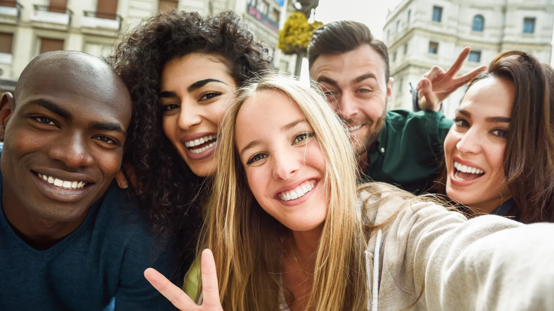 Group of diverse friends smiling and taking a selfie outdoors in an urban setting showing friendship and joy