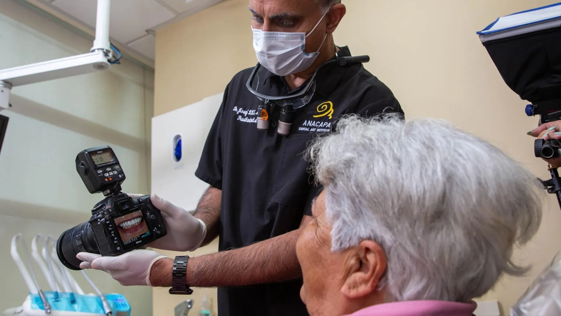 Dentist showing camera to patient during a dental consultation in a clinic setting.